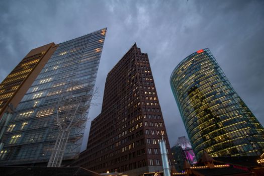 Illuminated skyscrapers reaching into an overcast sky in a bustling urban center.
