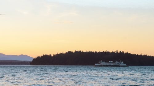 Free A picturesque ferry cruising at sunset near a forested island with serene water views. Stock Photo