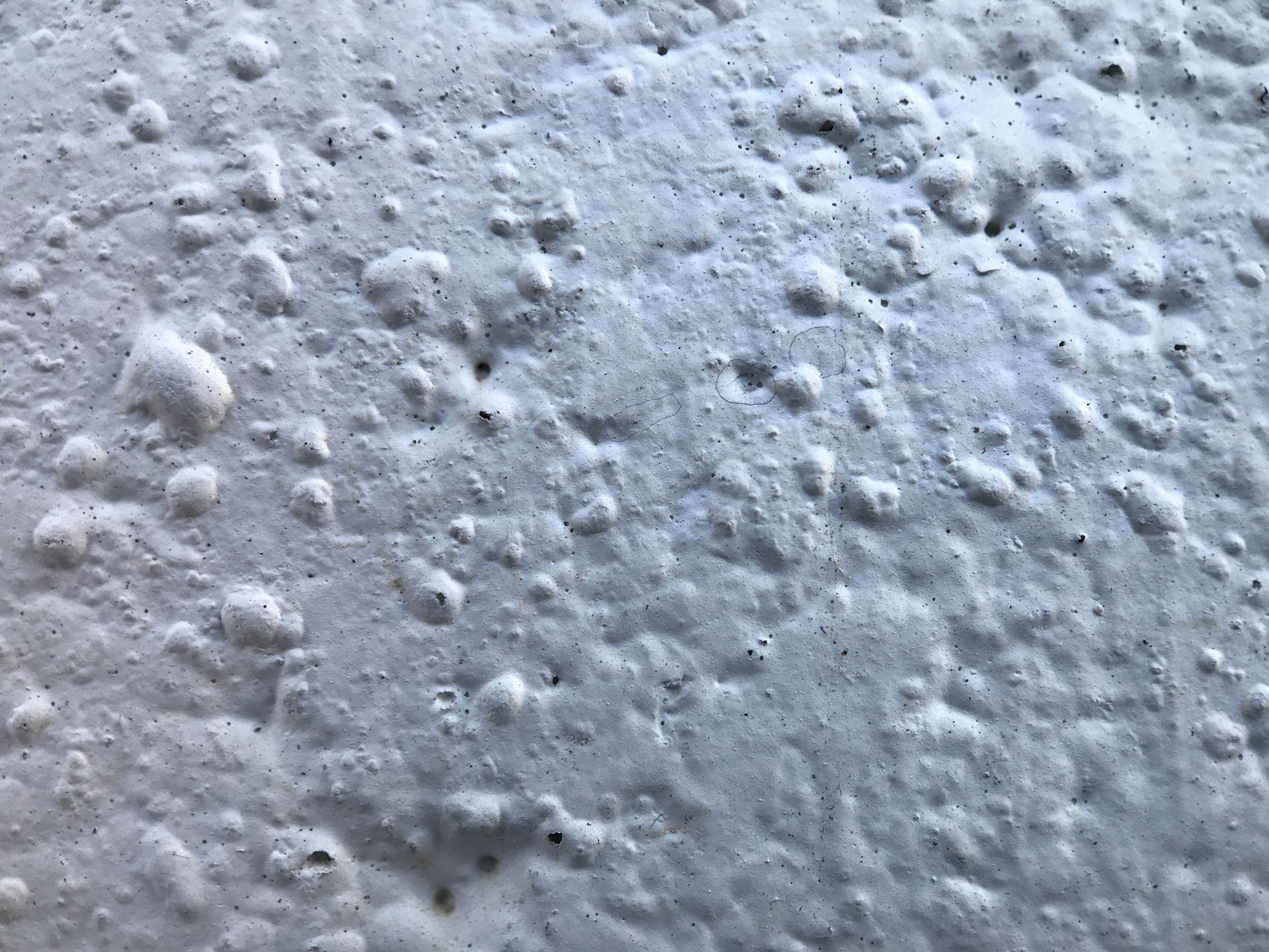 Detailed close-up of a white textured wall with a porous surface in natural light.