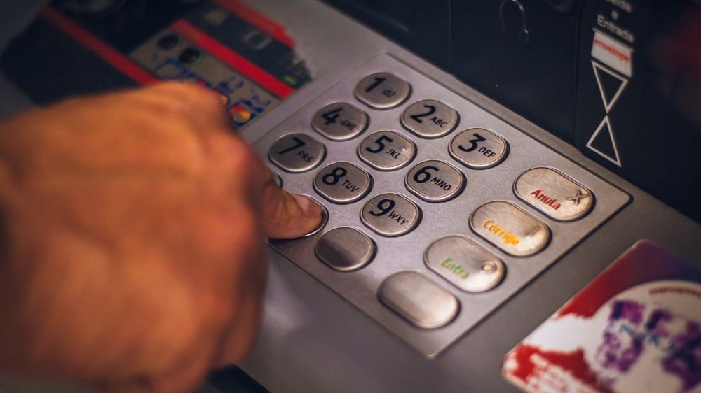 A hand pressing a button on an ATM keypad in Brasil, emphasizing digital banking.