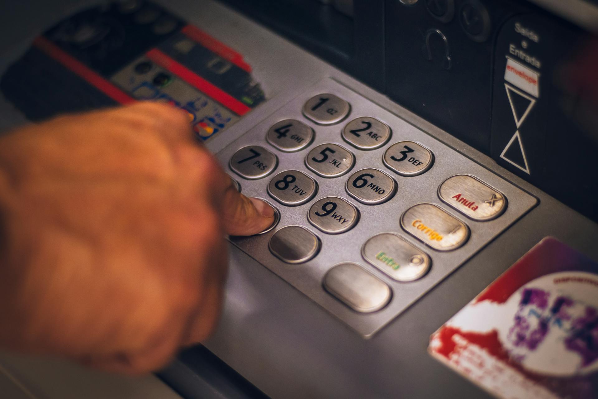 A hand pressing a button on an ATM keypad in Brasil, emphasizing digital banking.