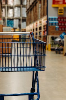 Side view of an empty shopping cart in a warehouse supermarket aisle with blurred merchandise.