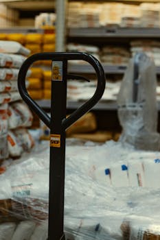 Pallet truck in an industrial warehouse with stacked goods.