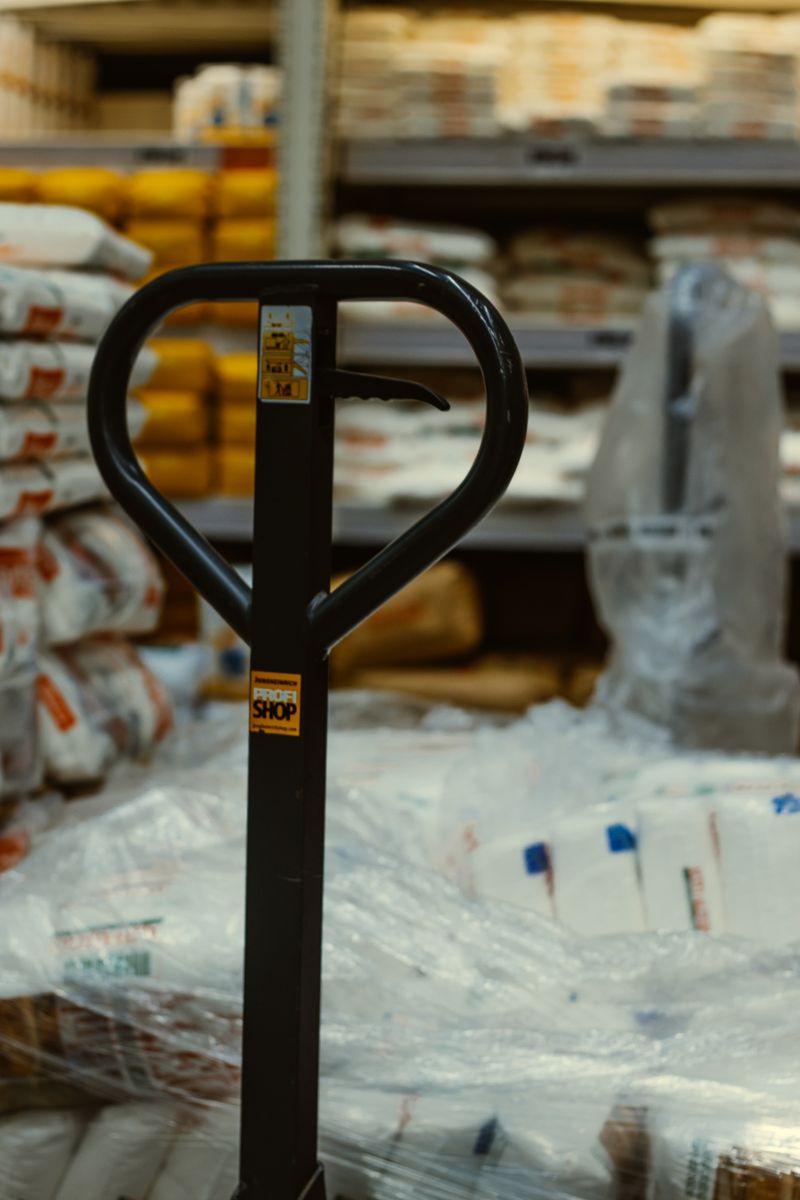 Pallet truck in an industrial warehouse with stacked goods