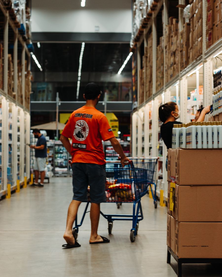Cliente com carrinho em corredor de supermercado