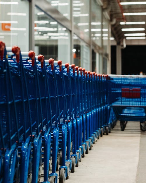 Blue Shopping Cart on Beside a Glass Wall