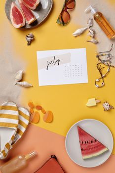 A vibrant summer-themed flat lay featuring watermelon, seashells, and a July calendar.