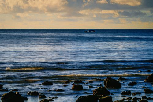 Free Tranquil seascape of a lone boat on a calm ocean, capturing the soothing horizon in Hainan, China. Stock Photo