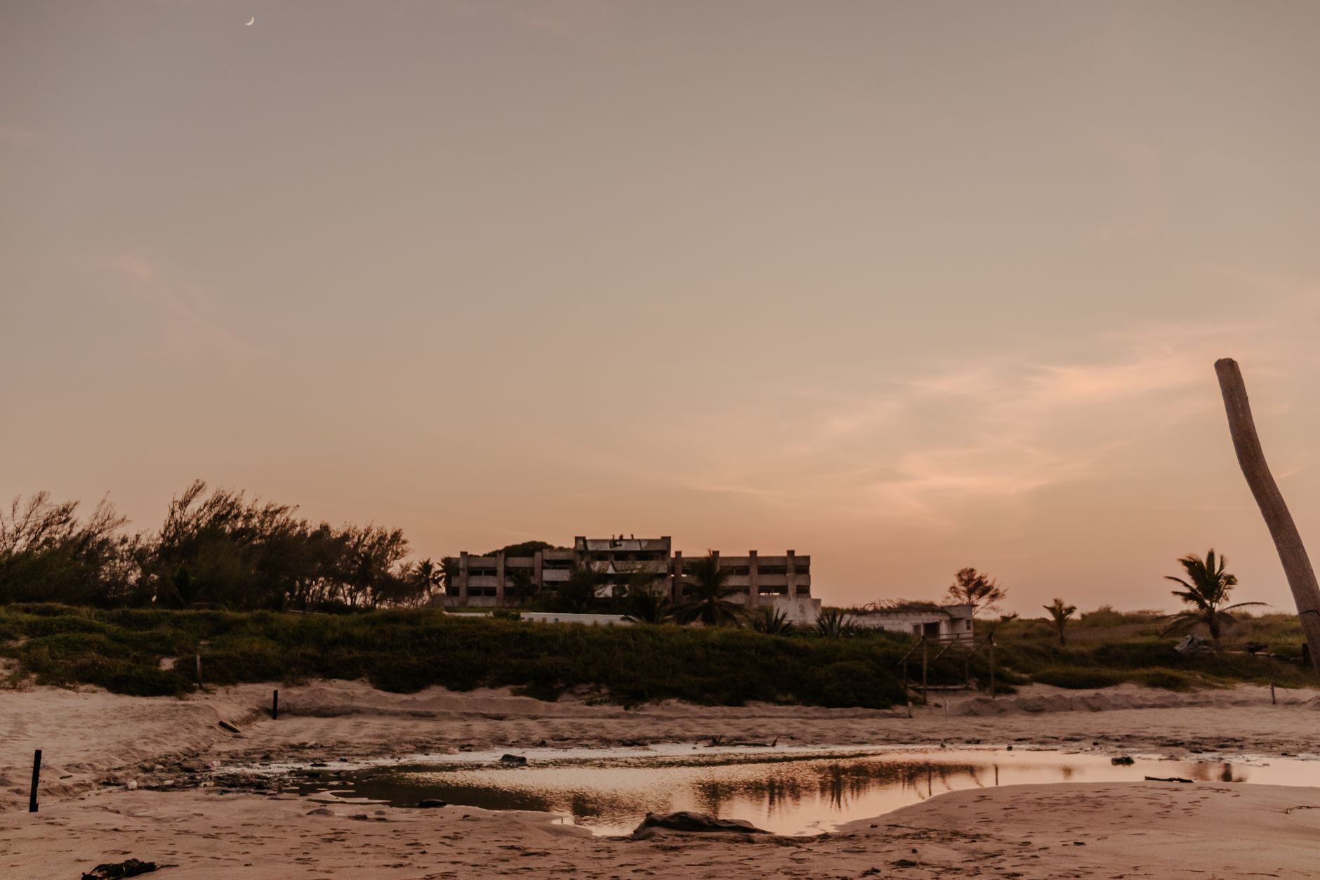 Tranquil sunset view of a beach in Ciudad Madero, Mexico with calm reflections and distant structures.