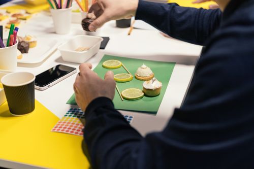 Free Hands decorating cupcakes with lemon slices in a vibrant indoor setting. Stock Photo