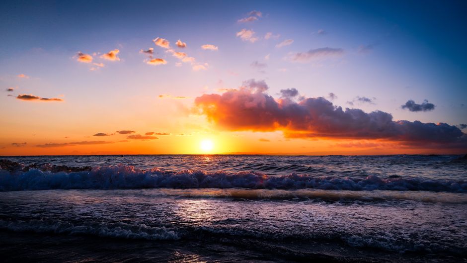 Capture the tranquility of a vibrant ocean sunset with colorful skies and gentle waves.