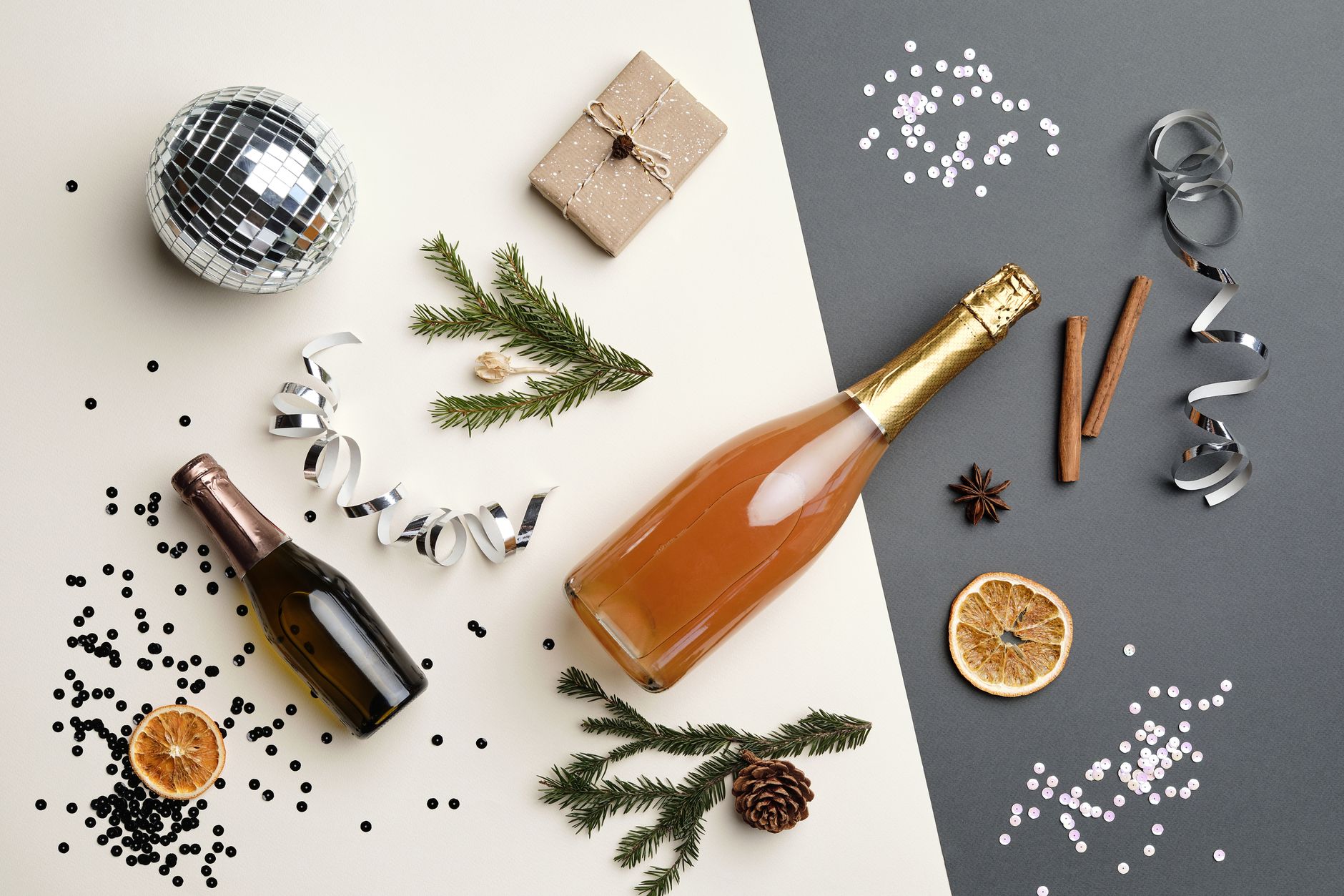 Festive flat lay with champagne bottles, disco ball, and holiday decor, perfect for New Year celebrations.