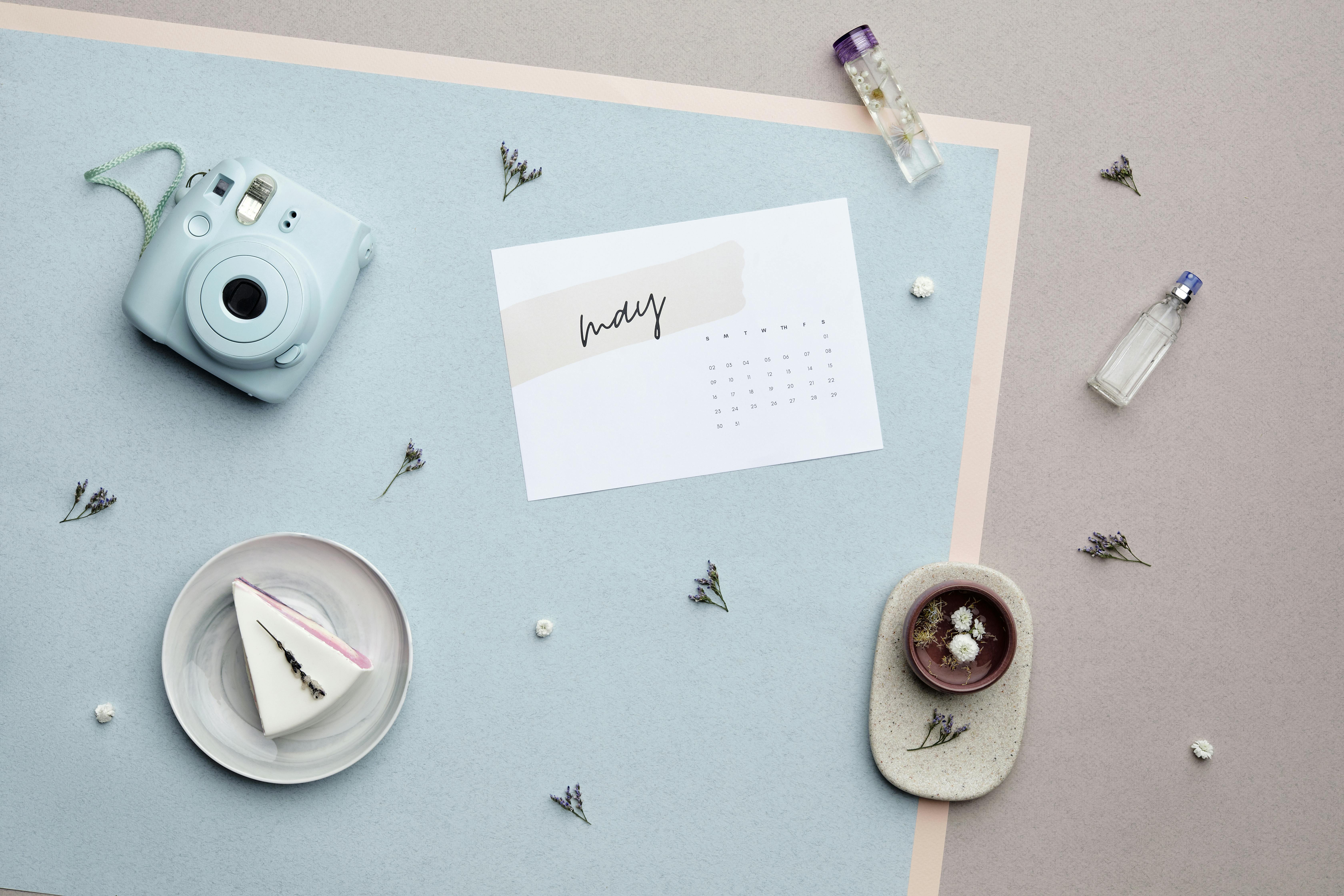 Minimalistic flat lay featuring a slice of cake, camera, and calendar page.