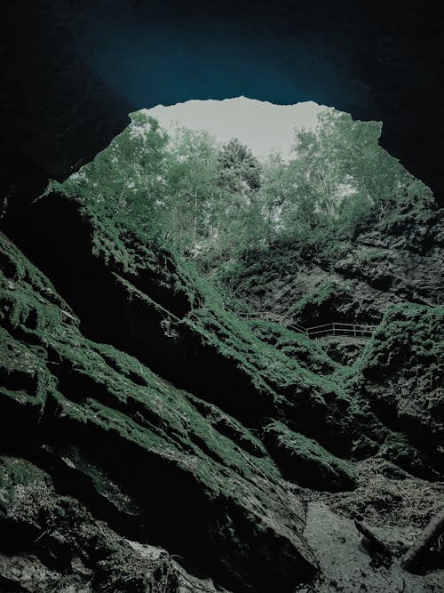 Scenic view of green grotto in rough mountains near bright trees in twilight