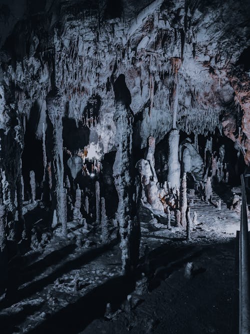 Scenic view of cave in bristly mountains with barren terrain and shades in twilight