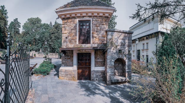 Rustic stone building amidst a lush, serene urban environment with unique architecture.