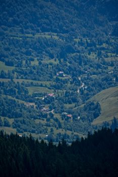 From above of greenery mount with lush trees on lawns near dwelling buildings in evening