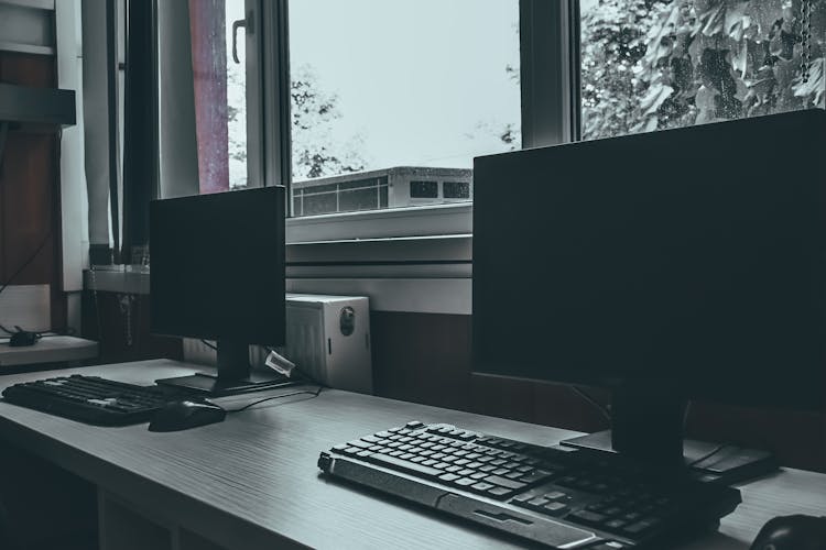 Modern Computers On Desk Near Window