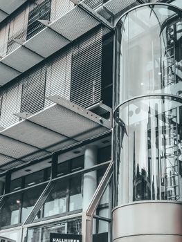 白天，高层多层建筑的简单大壁架上，长透明圆柱形电梯清晰可见