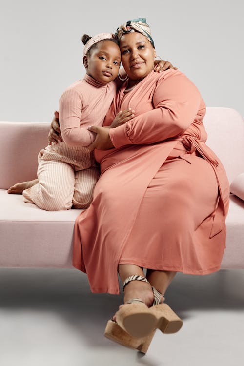 Free A Woman Embracing a Young Girl while Sitting on a Sofa Stock Photo