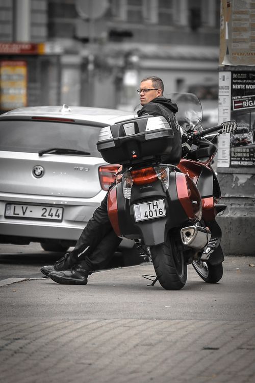 Free A man leans against a motorcycle in the city streets of Riga, Latvia. Stock Photo
