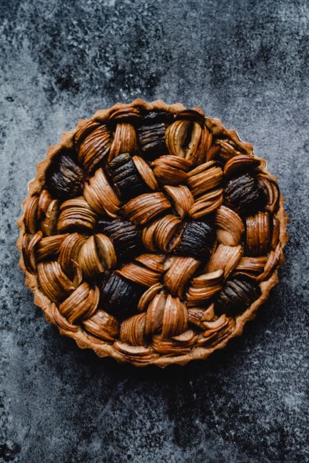 A beautifully baked pie with a braided crust, shot from above on a textured surface.