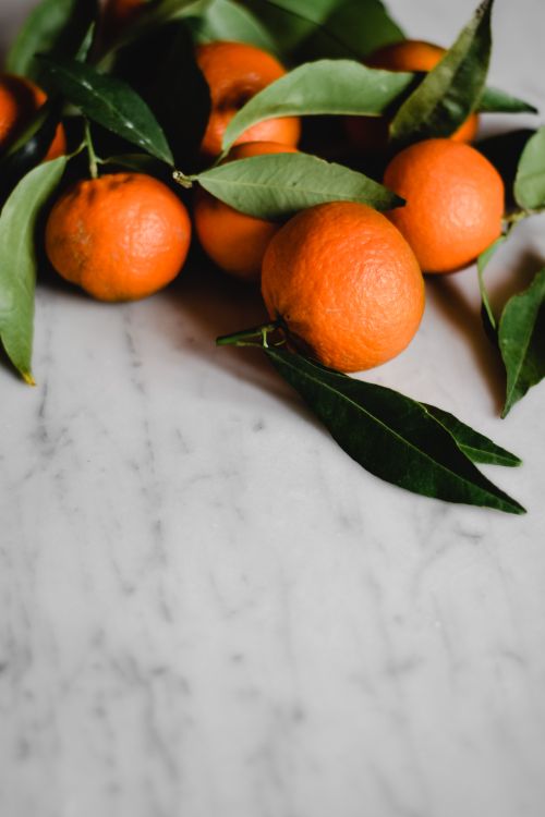 Free Vibrant oranges with green leaves on a marble surface, perfect for culinary and lifestyle themes. Stock Photo