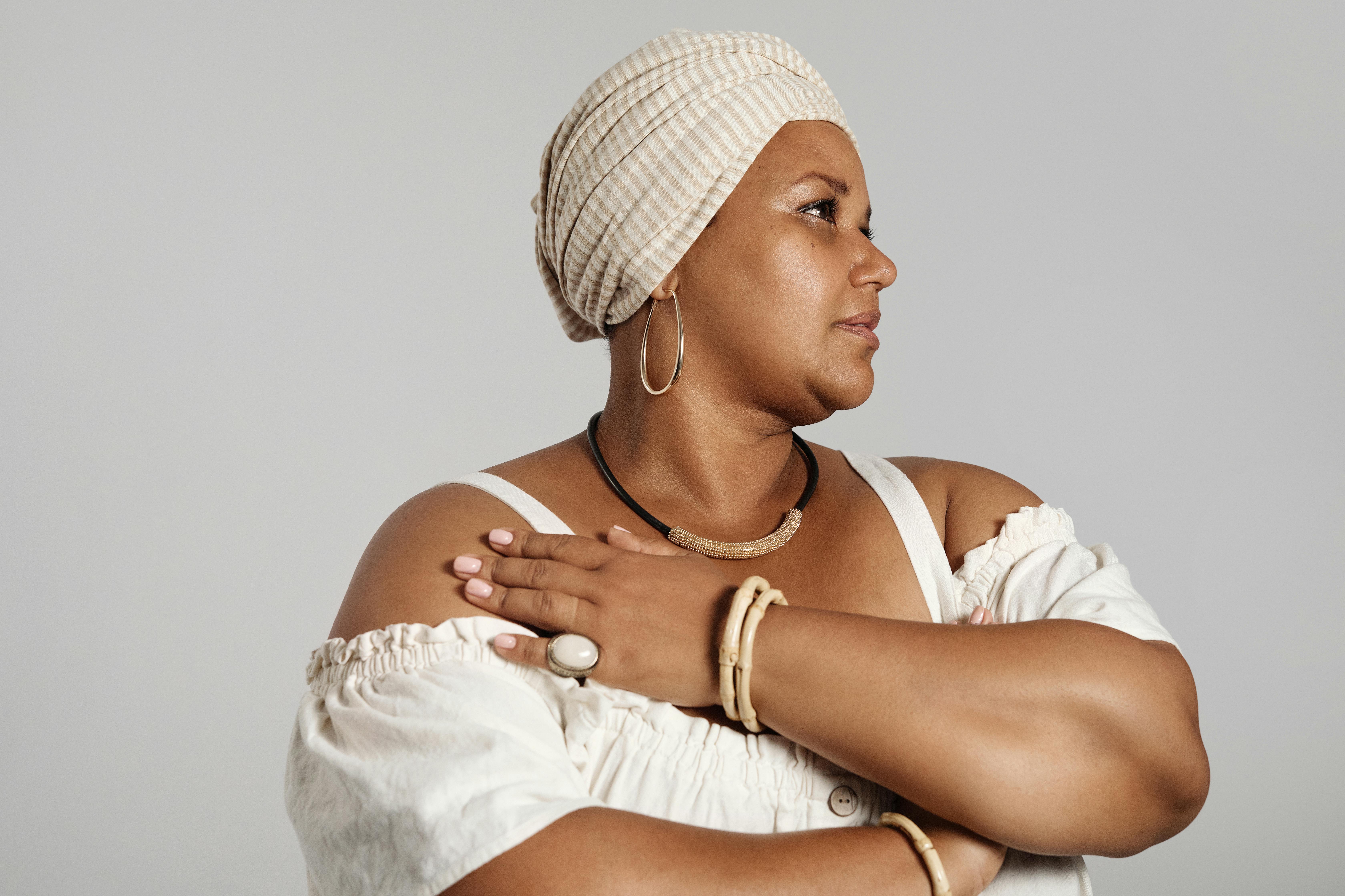Portrait of an elegant woman wearing a headscarf and jewelry in a studio setting.