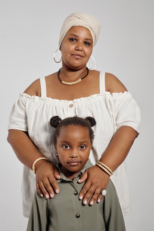 Woman in Beige Colored Turban holding her Daughter's Shoulder 