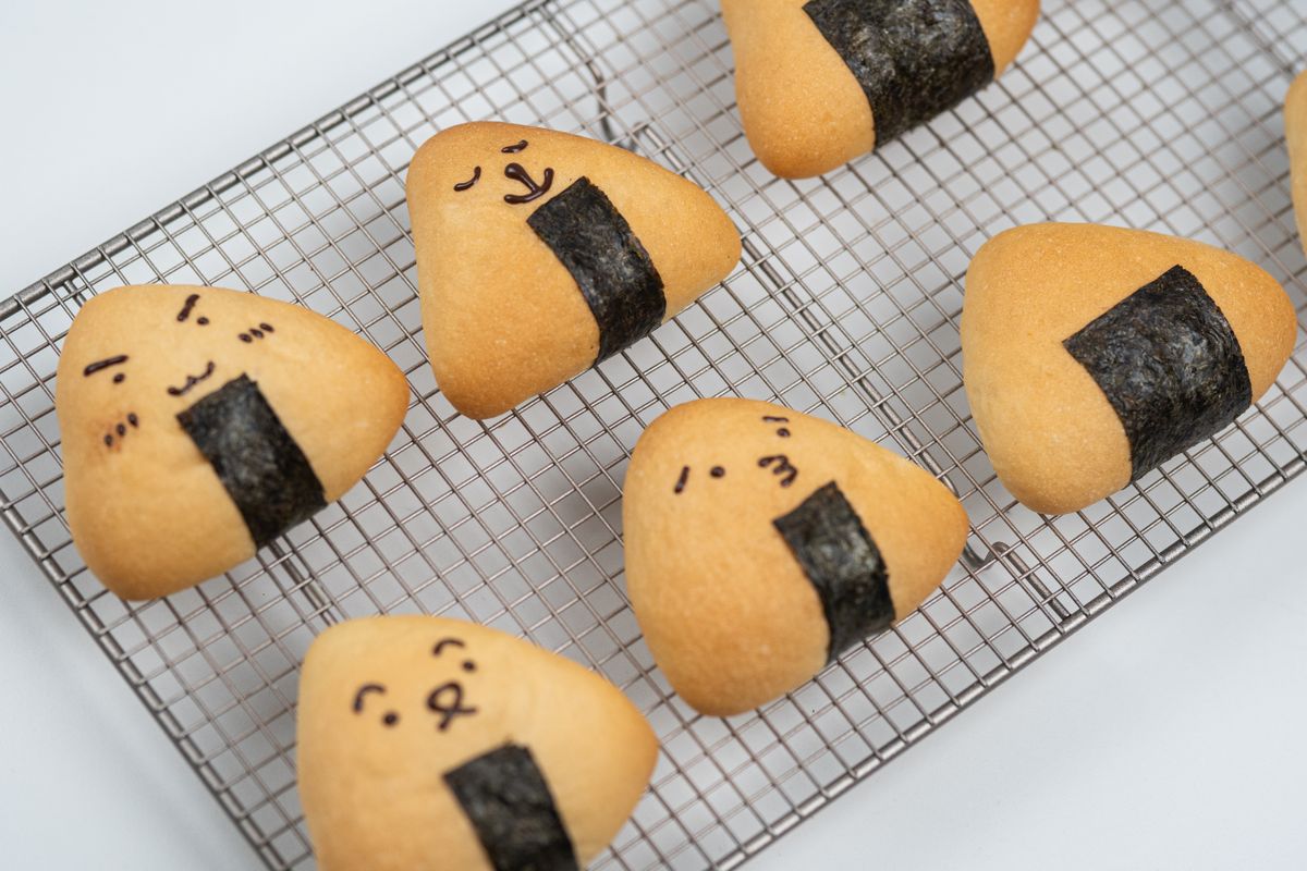 Kawaii onigiri cookies with nori seaweed faces on a soft pastel background