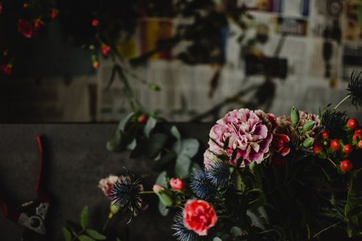 深色、艺术化的花卉排列，点缀着粉红色的康乃馨和绿叶