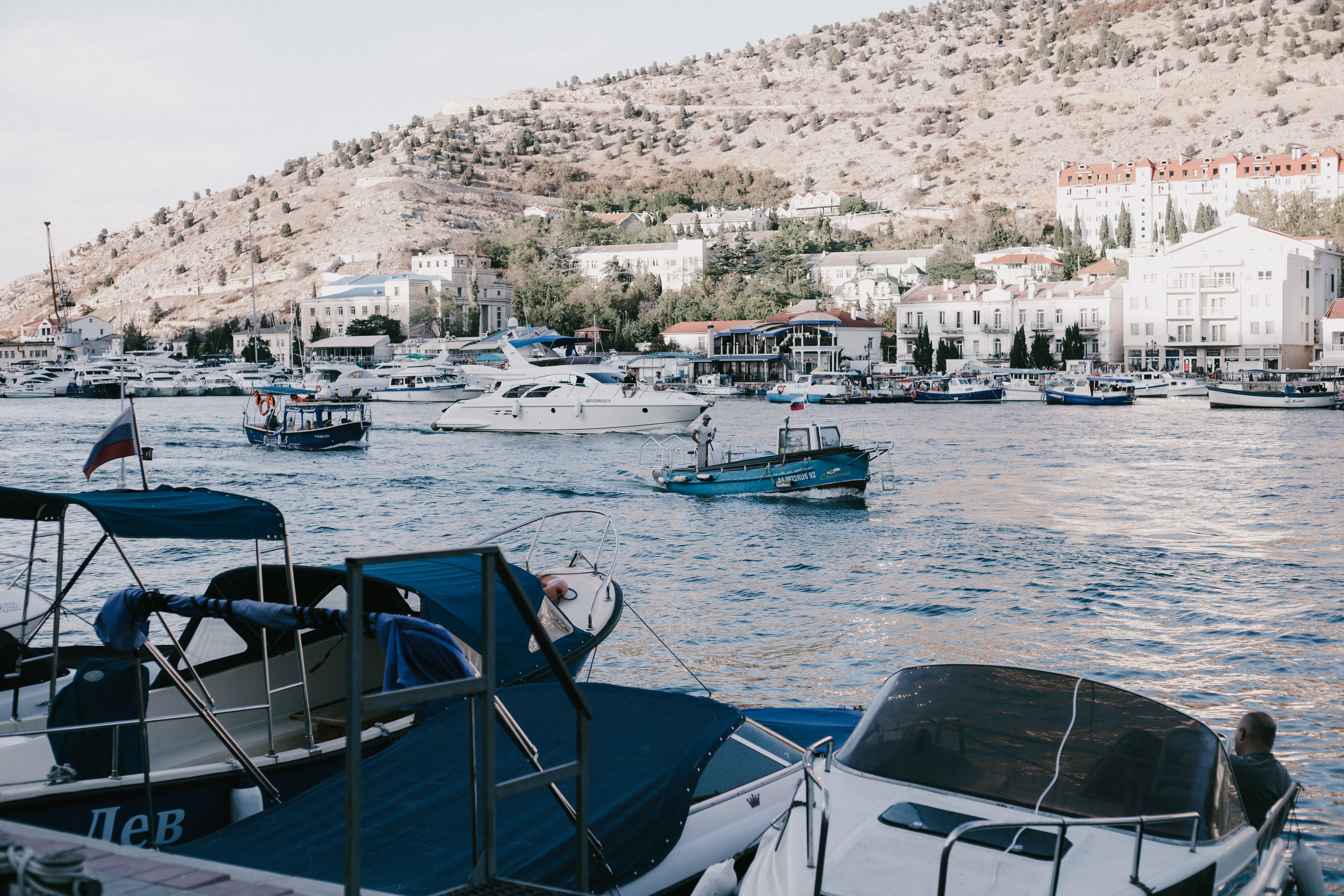 A peaceful harbor with yachts and motorboats anchored by a picturesque coastal town.