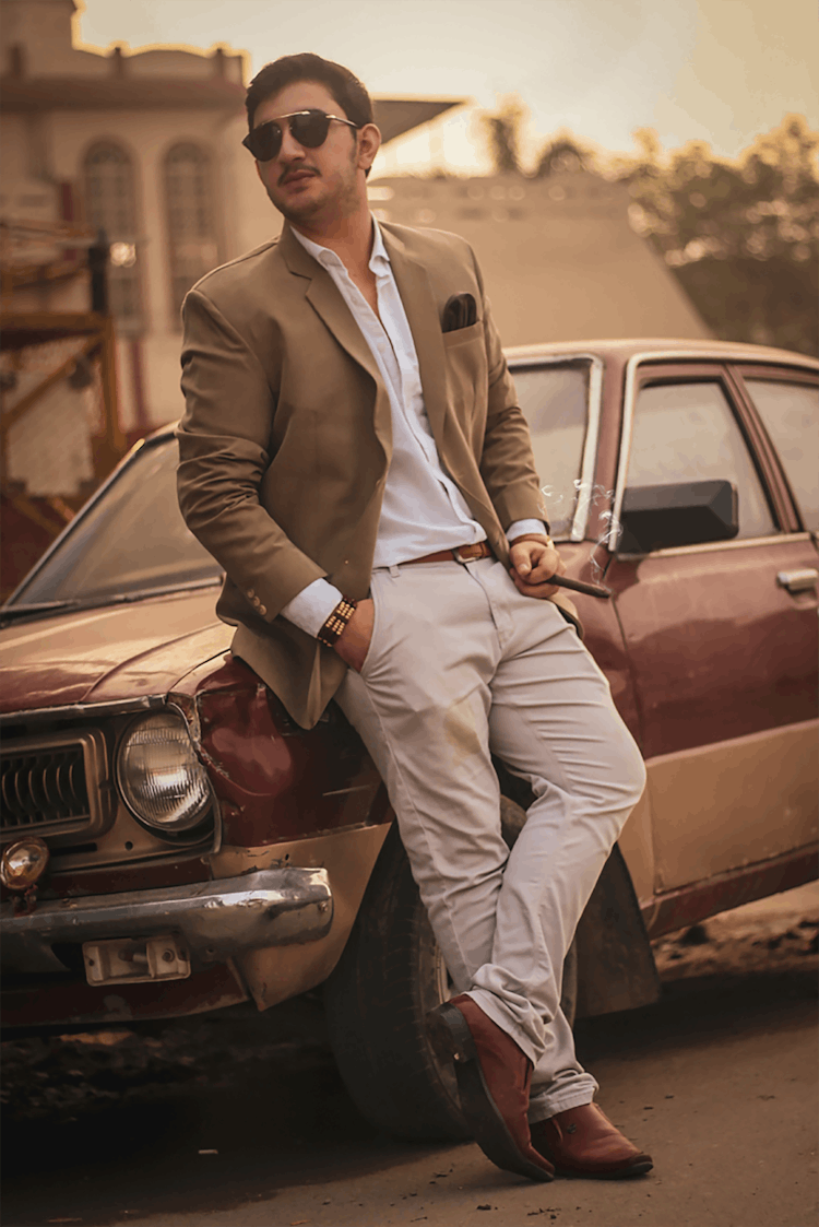 A Man In A Brown Suit Leaning On A Vintage Car