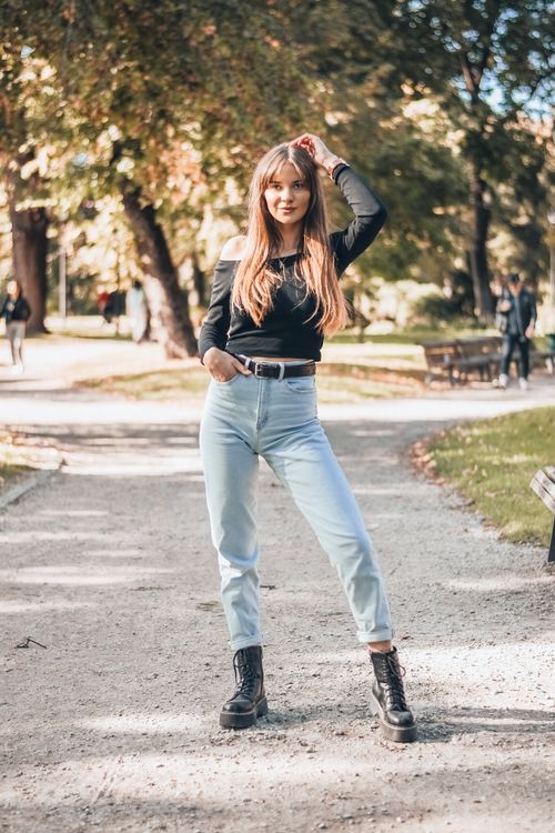 Free A stylish woman posing confidently on a sunny park pathway, showcasing fashion and elegance. Stock Photo