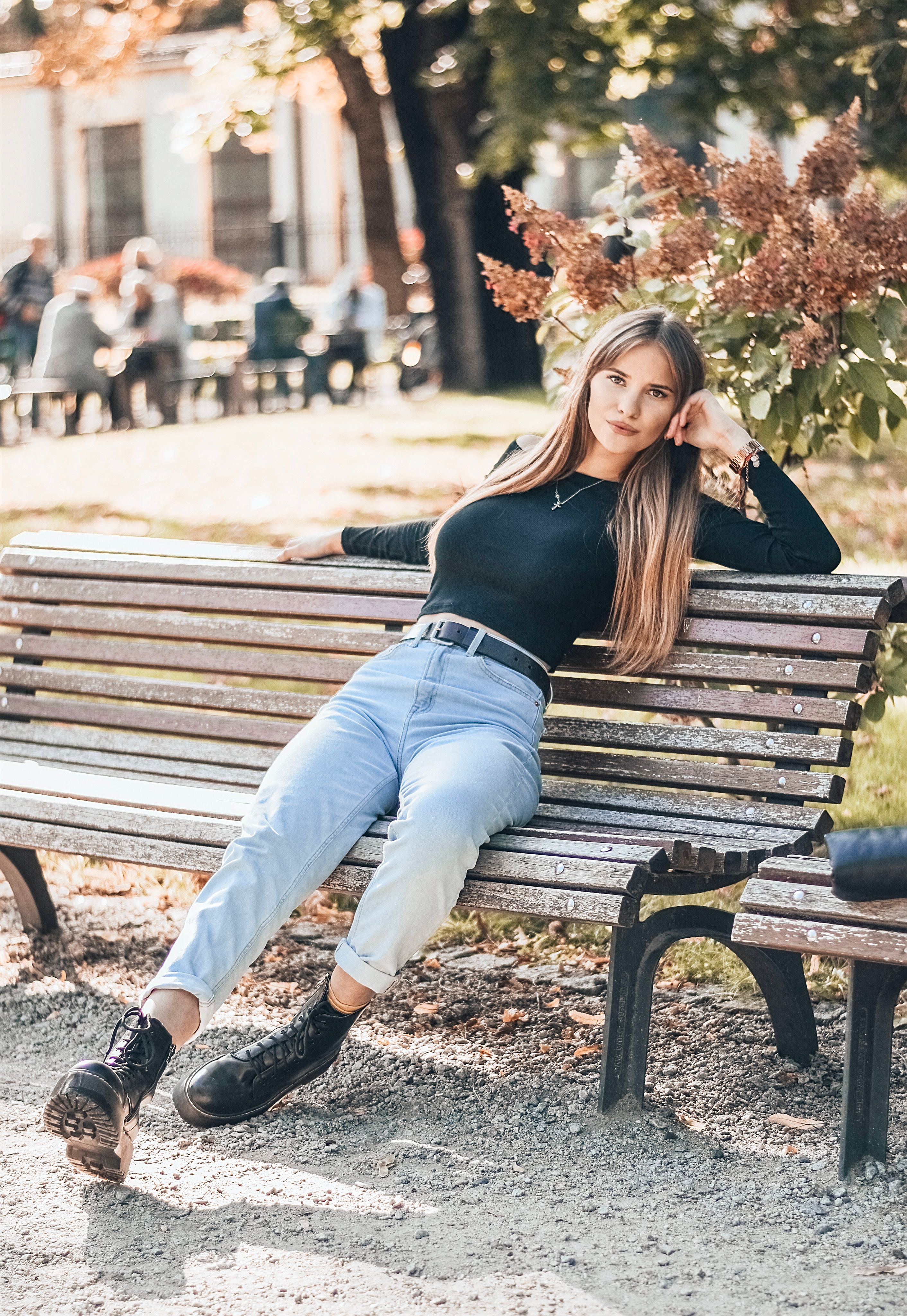 A Woman in Black Long Sleeves and Denim Pants Sitting on Brown Wooden ...