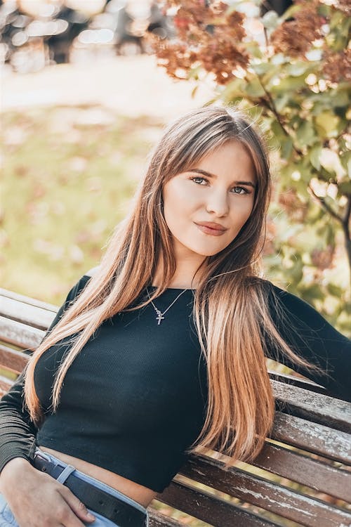 A Woman in Black Long Sleeve Shirt Sitting on Wooden Bench