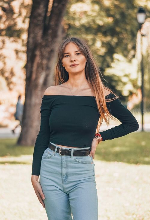 Free Stylish woman in off-shoulder top and jeans posing confidently outdoors. Stock Photo