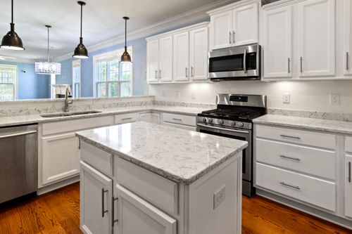 Free A bright, spacious kitchen with marble countertops, stainless steel appliances, and elegant white cabinetry. Stock Photo