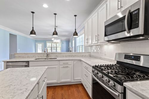 Free Sleek kitchen featuring stainless steel appliances and marble countertops under pendant lighting. Stock Photo