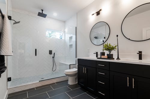 Bathroom with Black Cabinets, Round Mirrors and Glass Shower Cabin