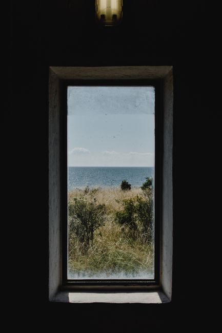 A serene seaside view framed by a window in Sääre offers a glimpse of nature's beauty.