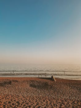 Serene sunset on the pebbly shores of Brighton, England, with a tranquil sea and pastel sky.