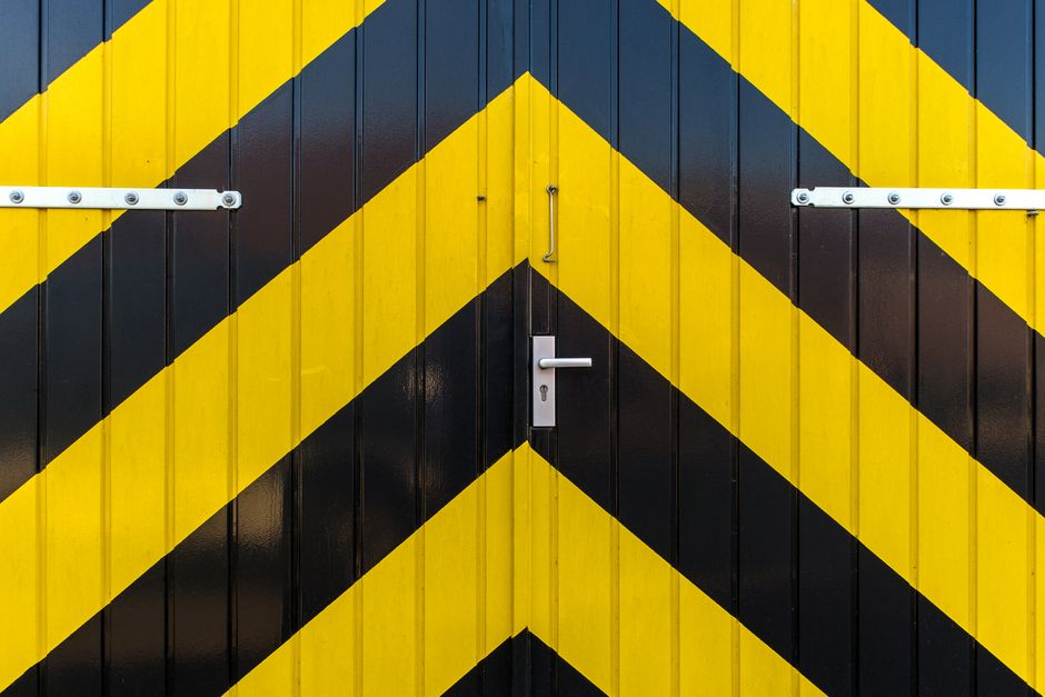 Close-up of a metal door with striking yellow and black diagonal stripes and a metallic handle.