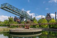 Red and Black Metal Crane Near Green Trees Under Blue Sky