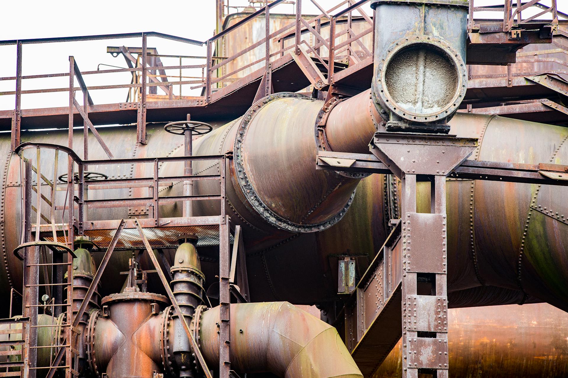 Detailed view of a rusty industrial pipe system showcasing robust metal construction and aged textures.