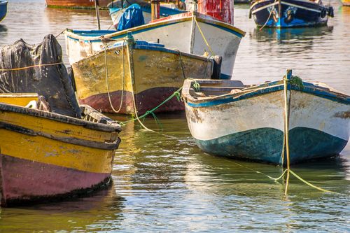 Free Vibrant wooden boats docked along a calm river, perfect for fishing. Stock Photo