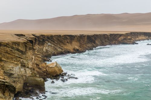 Free Scenic view of rugged coastline with waves crashing against rocky cliffs under a cloudy sky. Stock Photo