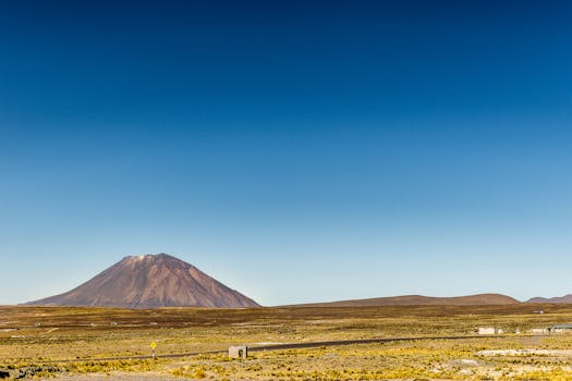 A vast and clear landscape with a prominent volcano under a deep blue sky, showcasing natural beauty.