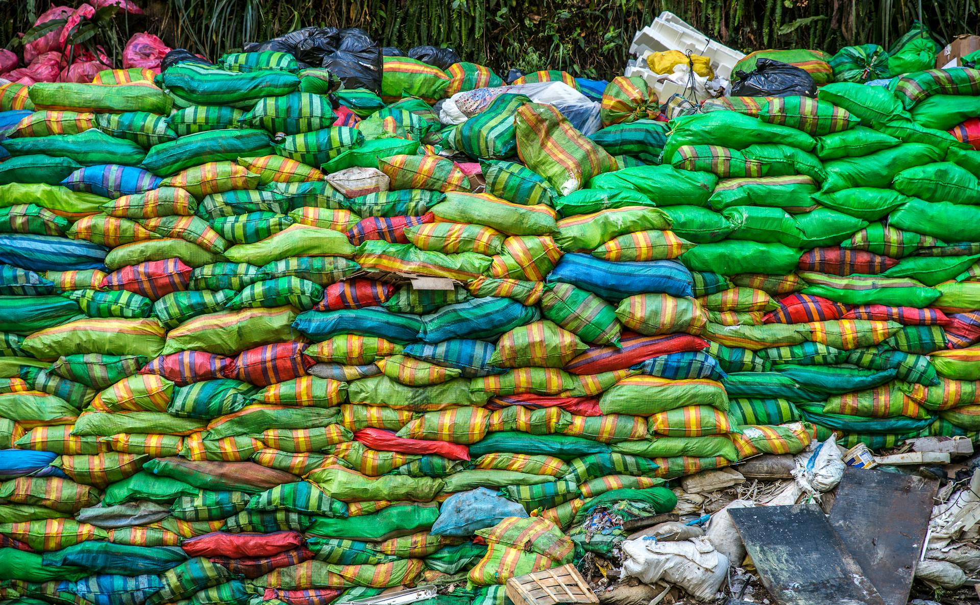 A vibrant collection of multicolored sacks stacked in an outdoor setting, showcasing variety and abundance.