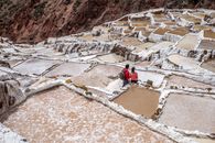 Man in Red Jacket Sitting on Brown Rock Formation